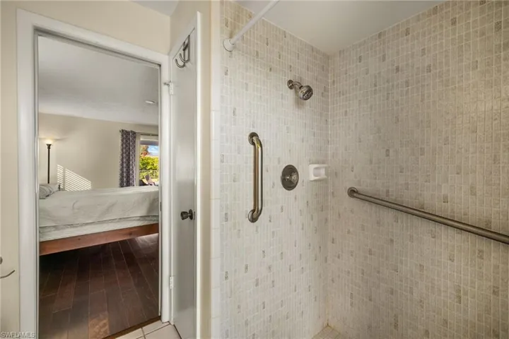 Bathroom with tiled shower and hardwood / wood-style flooring