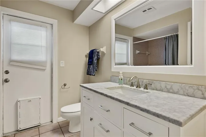 Bathroom featuring tile patterned flooring, vanity, toilet, and walk in shower
