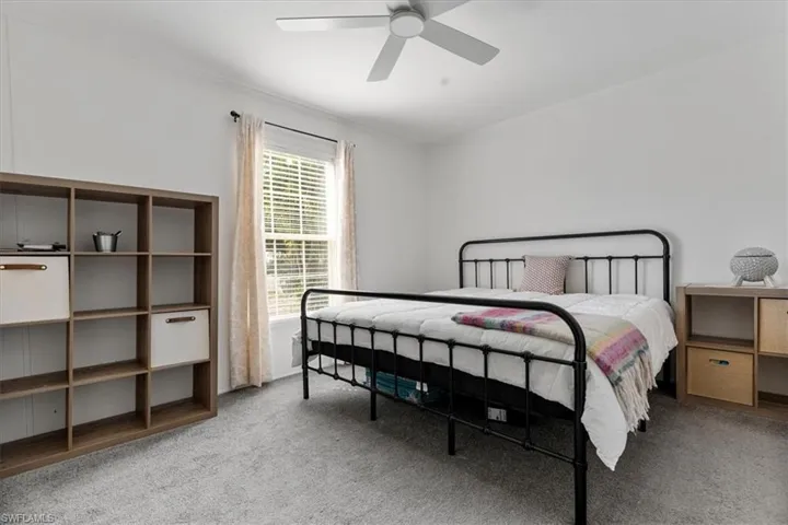 Carpeted bedroom with ceiling fan and ornamental molding