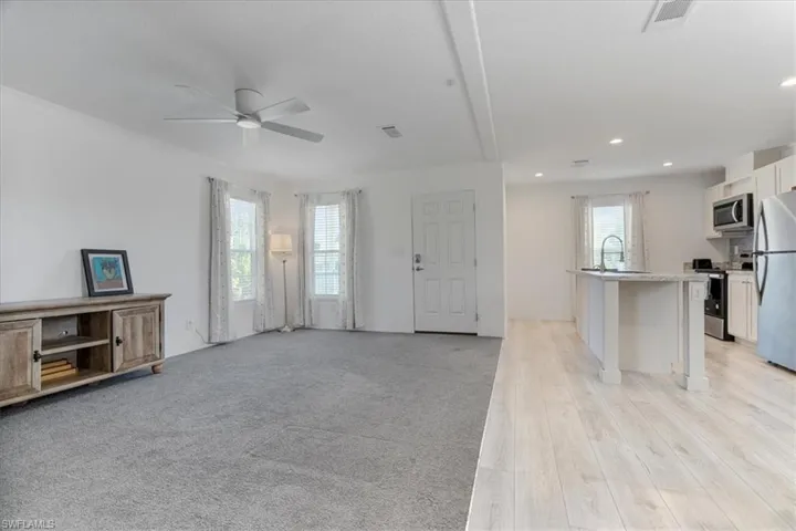 Living room featuring sink, light carpet, and ceiling fan