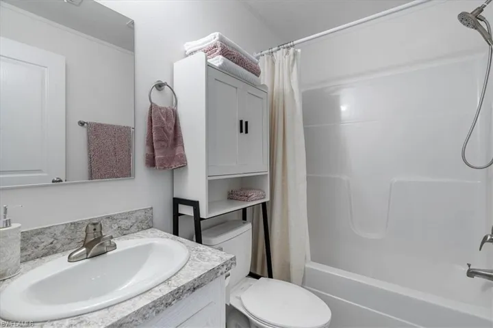 Full bathroom with shower / tub combo with curtain, vanity, and toilet