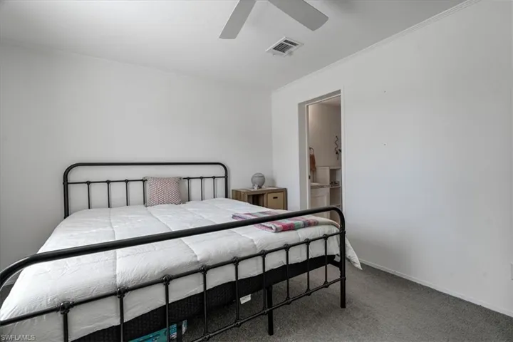 Carpeted bedroom featuring ornamental molding and ceiling fan