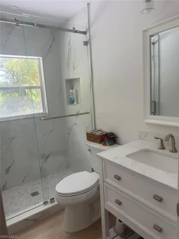 Bathroom with vanity, a marble finish shower, and wood finished floors