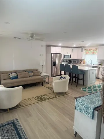 Living area with light wood-style floors, a ceiling fan, and recessed lighting