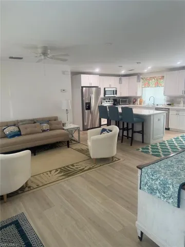 Living room with light wood-style flooring, a ceiling fan, and recessed lighting