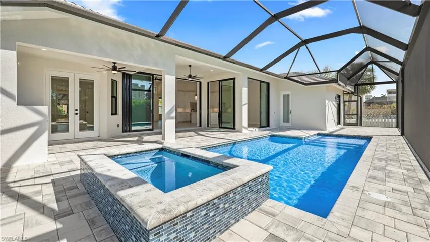 Integrated pool / hot tub with a sunroom, french doors, a patio area, and a lanai