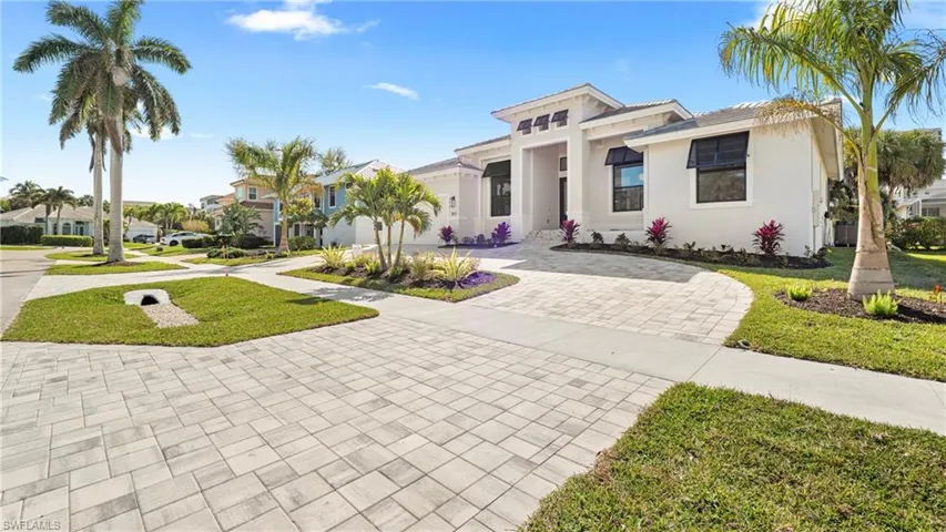View of front facade with curved driveway, a front lawn, stucco siding, and a residential view