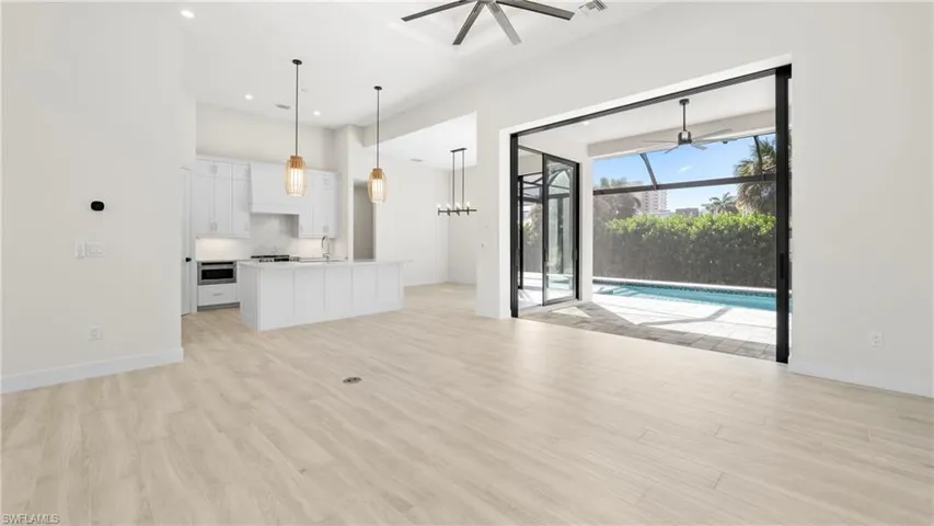 Unfurnished living room with ceiling fan, light wood finished floors, a high ceiling, and recessed lighting
