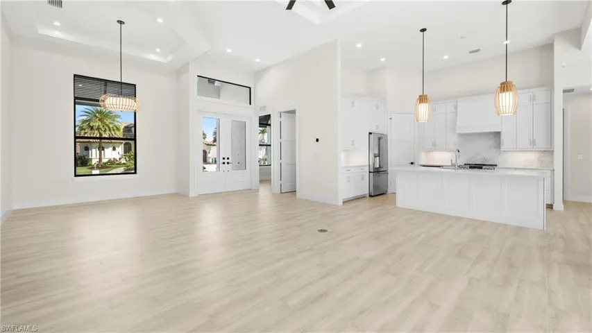 Unfurnished living room featuring plenty of natural light, a high ceiling, light wood finished floors, and recessed lighting