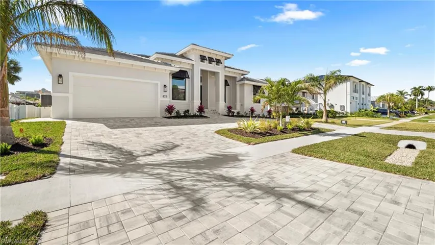 View of front of house with driveway, a garage, stucco siding, and a front lawn