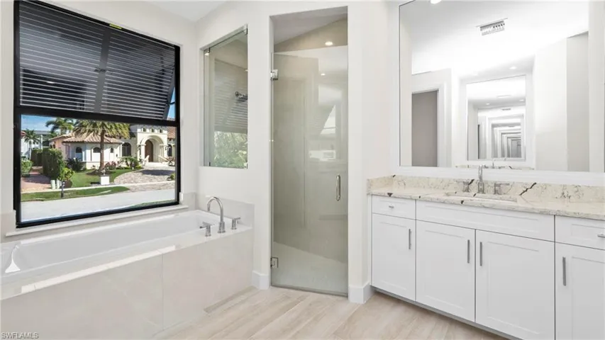Bathroom with vanity, a shower stall, a garden tub, and light wood-style floors