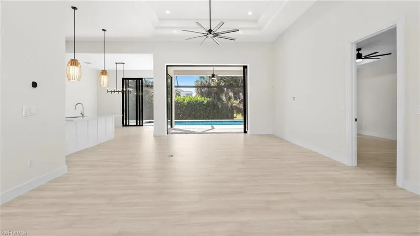 Unfurnished dining area featuring a ceiling fan, light wood-type flooring, a sunroom, and a raised ceiling