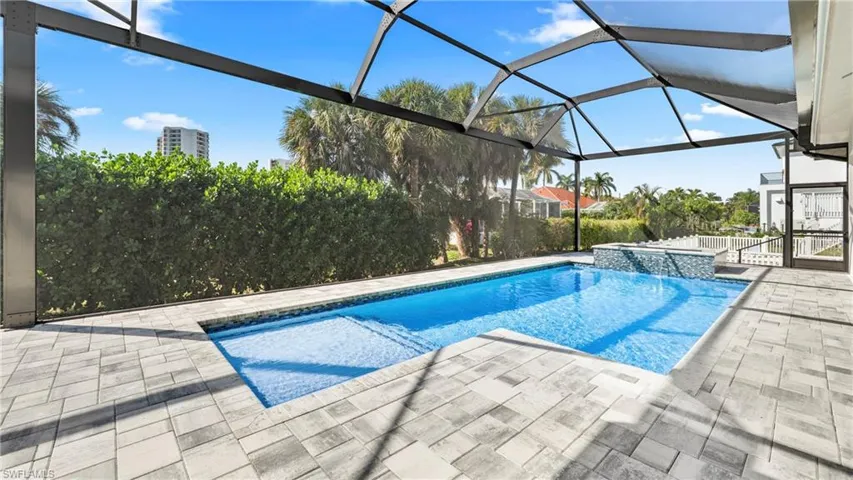 Outdoor pool with a hot tub, a patio area, a sunroom, and glass enclosure