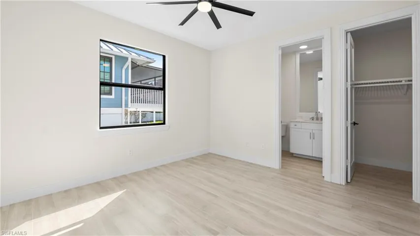Unfurnished bedroom featuring a spacious closet, light wood-style flooring, and a ceiling fan