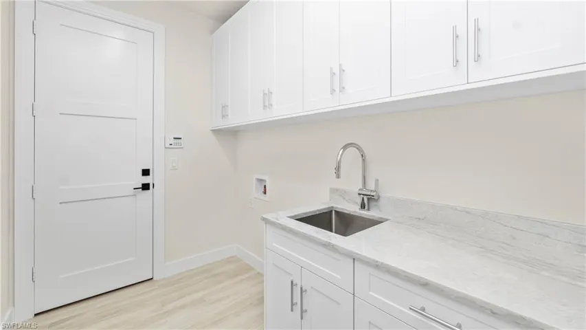 Laundry area with cabinet space, washer hookup, and light wood-style flooring