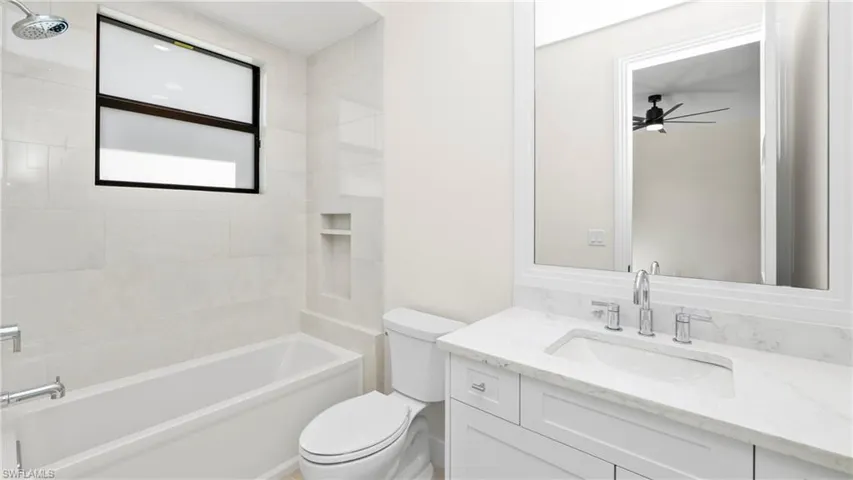 Bathroom with vanity, washtub / shower combination, and a ceiling fan