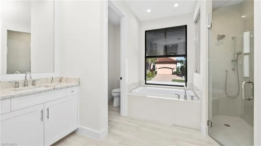 Bathroom featuring a stall shower, vanity, a bath, recessed lighting, and light wood-style floors