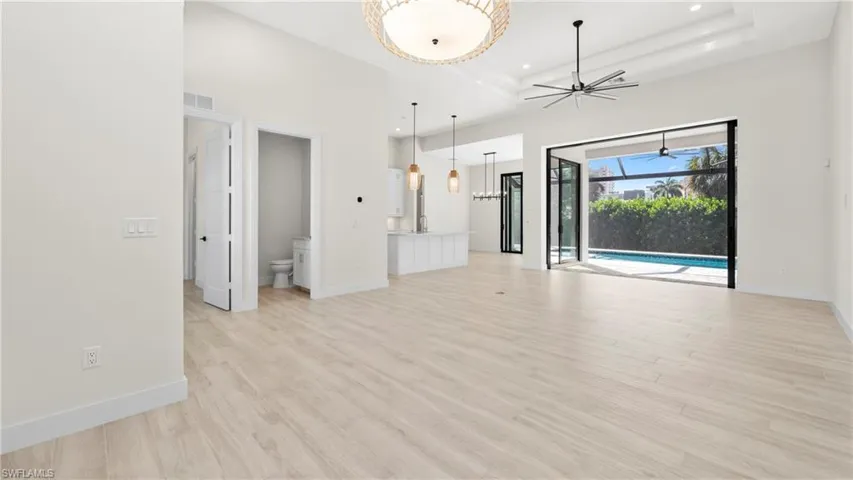 Unfurnished living room featuring light wood-style flooring, a ceiling fan, recessed lighting, and a high ceiling