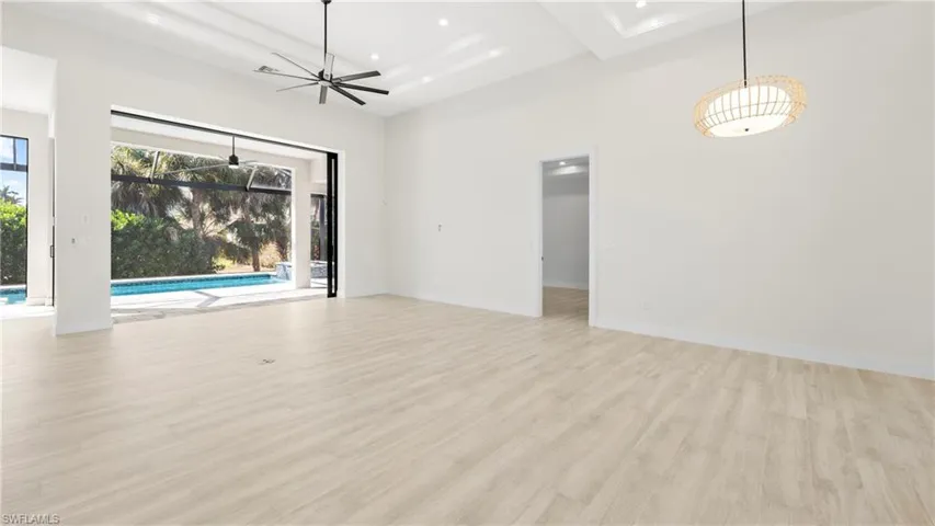 Unfurnished room featuring recessed lighting, light wood finished floors, a sunroom, a high ceiling, and ceiling fan