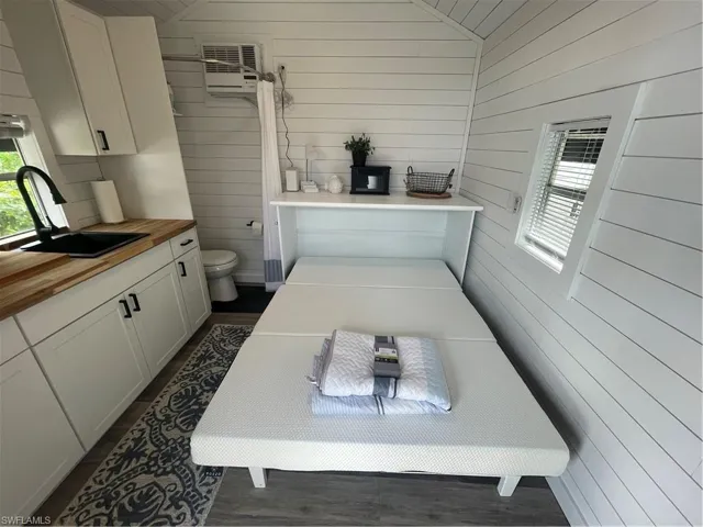 Bathroom featuring wooden walls, lofted ceiling, vanity, and a wall mounted air conditioner