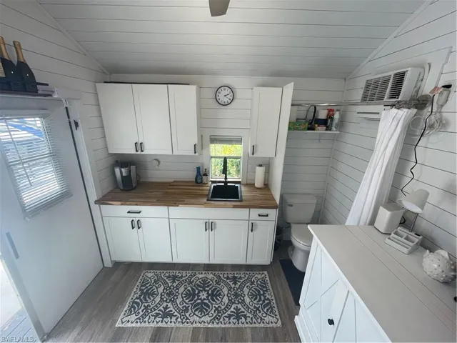 Kitchen featuring lofted ceiling, white cabinets, wood walls, dark wood finished floors, and wood counters