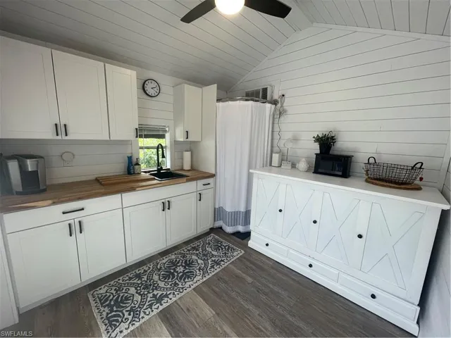 Kitchen with white cabinetry, lofted ceiling, wooden ceiling, wooden walls, and butcher block countertops