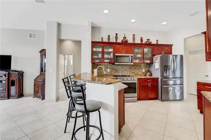 Kitchen with tasteful backsplash, a breakfast bar area, light tile patterned floors, kitchen peninsula, and stainless steel appliances