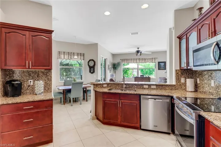 Kitchen with stainless steel appliances, a healthy amount of sunlight, sink, and light stone counters