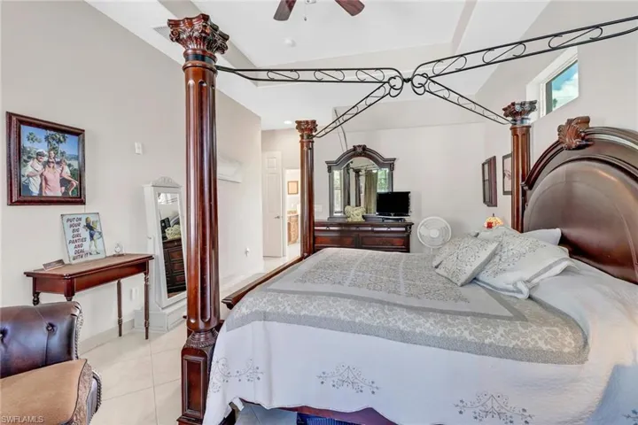 Bedroom featuring vaulted ceiling, ceiling fan, and light tile patterned flooring
