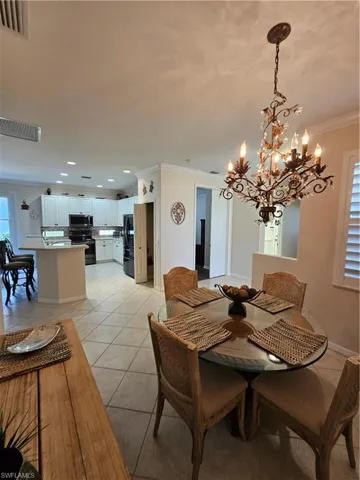 Dining area with crown molding, a chandelier, and light tile patterned floors