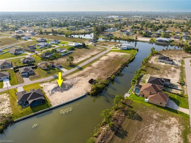 Aerial view of property and surrounding area featuring nearby suburban area and a nearby body of water