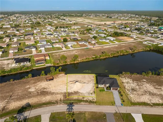 Aerial perspective of suburban area with property parcel outlined and a nearby body of water