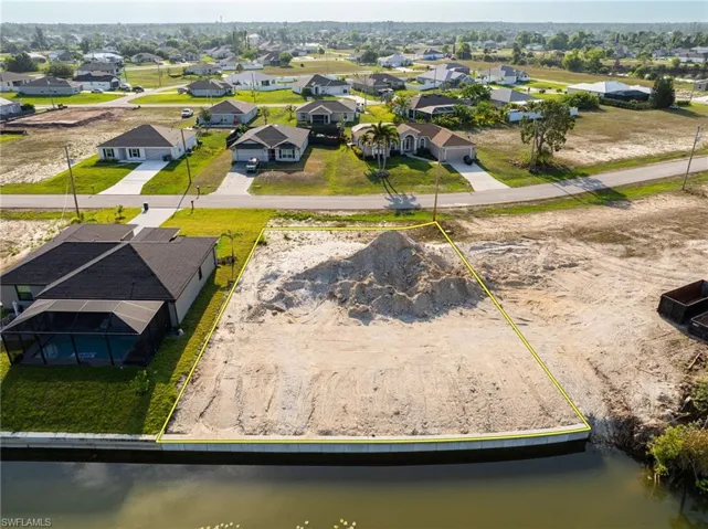 Aerial perspective of suburban area with property boundaries highlighted and a nearby body of water