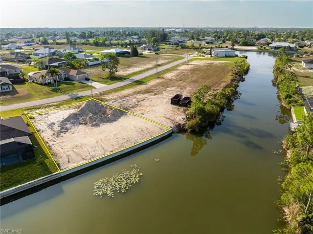 Aerial view of residential area with a nearby body of water and property boundaries highlighted