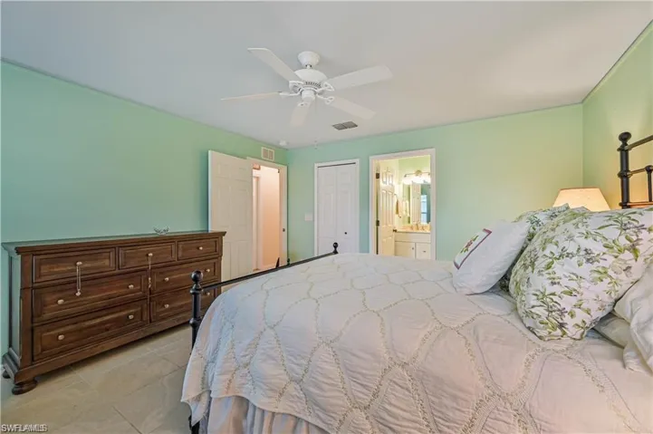 Tiled bedroom with ceiling fan, connected bathroom, and a closet