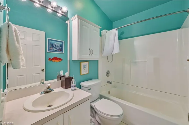 Full bathroom featuring shower / bathtub combination, vanity, lofted ceiling, and toilet