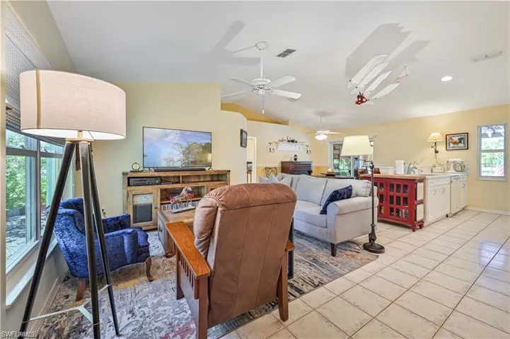 Living room featuring a wealth of natural light, light tile patterned floors, lofted ceiling, and ceiling fan