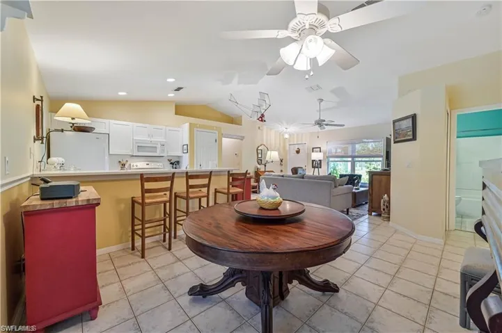 Dining room with ceiling fan, light tile patterned floors, and lofted ceiling
