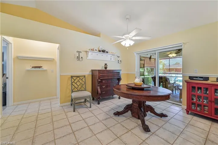Dining space featuring ceiling fan, light tile patterned floors, and lofted ceiling
