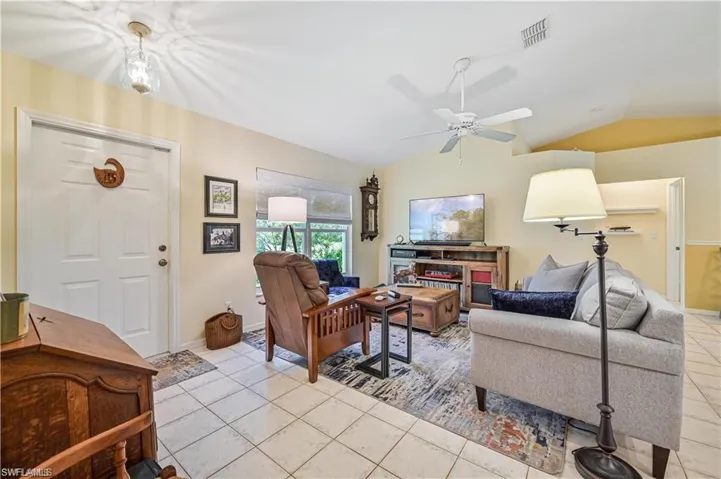 Tiled living room with ceiling fan and vaulted ceiling