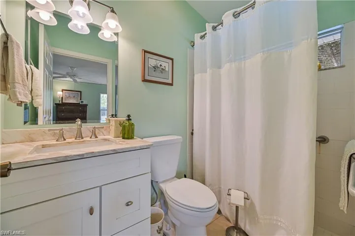 Bathroom with ceiling fan, curtained shower, toilet, and vanity