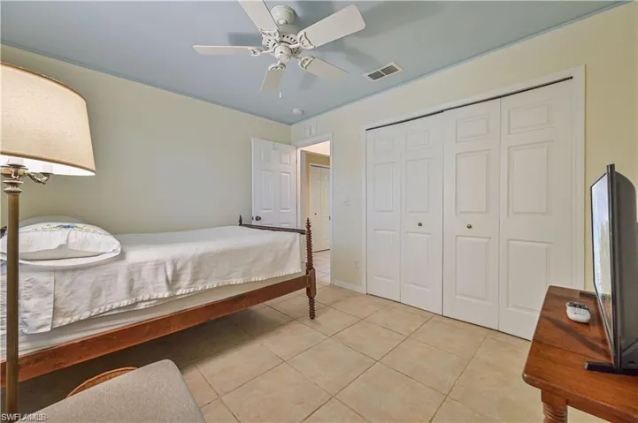 Tiled bedroom featuring ceiling fan and a closet