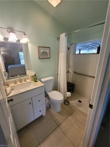 Bathroom featuring tile patterned floors, a shower with curtain, vanity, and toilet