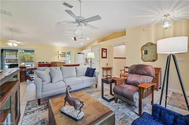 Tiled living room with ceiling fan and lofted ceiling