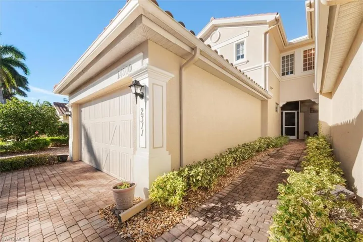 View of side of property with stucco siding, a garage, and decorative driveway