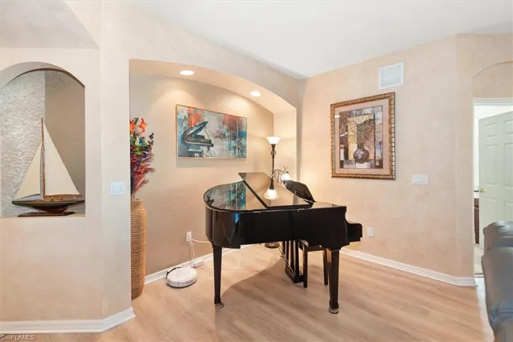 Sitting room featuring arched walkways, wood finished floors, recessed lighting, and a textured wall