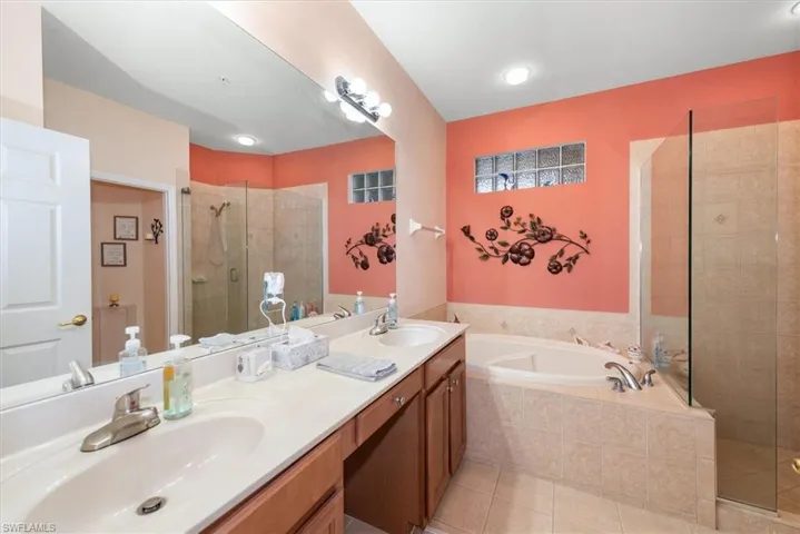 Bathroom featuring a shower stall, a bath, double vanity, and light tile patterned floors