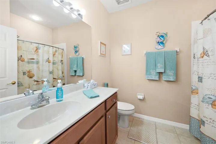 Full bath with light tile patterned flooring, vanity, and a shower with shower curtain