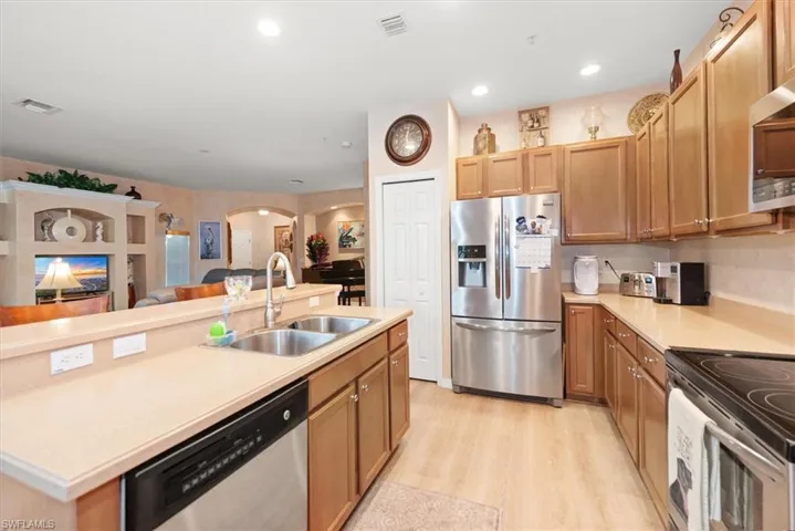 Kitchen with stainless steel appliances, light countertops, a center island with sink, open floor plan, and recessed lighting
