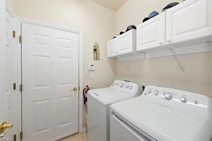 Laundry area featuring cabinet space, light tile patterned floors, and washer and dryer